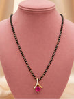 Gold-plated mangalsutra with fuchsia stone pendant displayed on a pink velvet jewellery bust