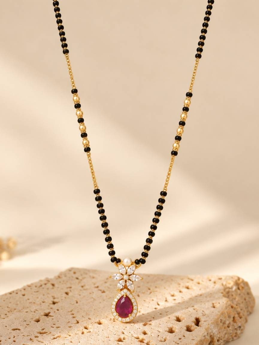 Ruby CZ and white CZ floral mangalsutra pendant on a textured stone surface in natural light