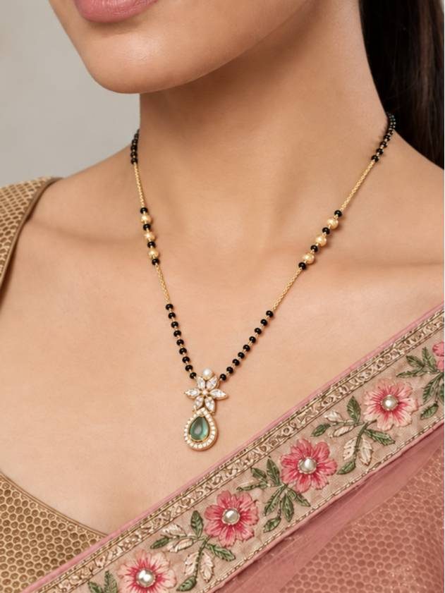 Model wearing gold-plated mangalsutra with emerald pendant over a pink embroidered saree