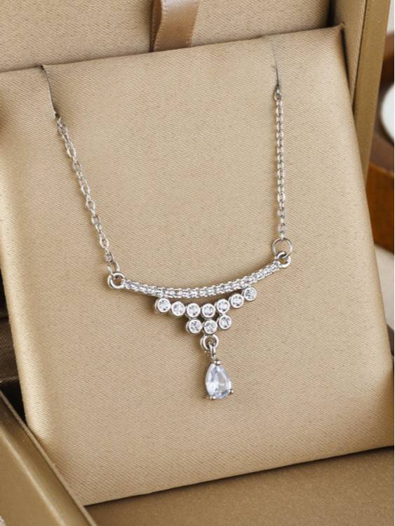 Silver-finish CZ drop necklace displayed on a tan jewellery box showing curved bar and teardrop pendant