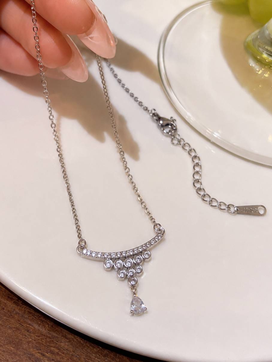 Silver CZ necklace held by hand showing lobster clasp, extender chain, and full pendant detail