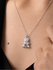 Model wearing silver teddy bear pendant necklace against bare collarbone with dark top
