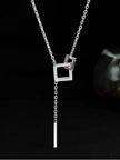 Silver-tone lariat necklace with two interlocked open squares and a slim bar drop hanging against a dark background