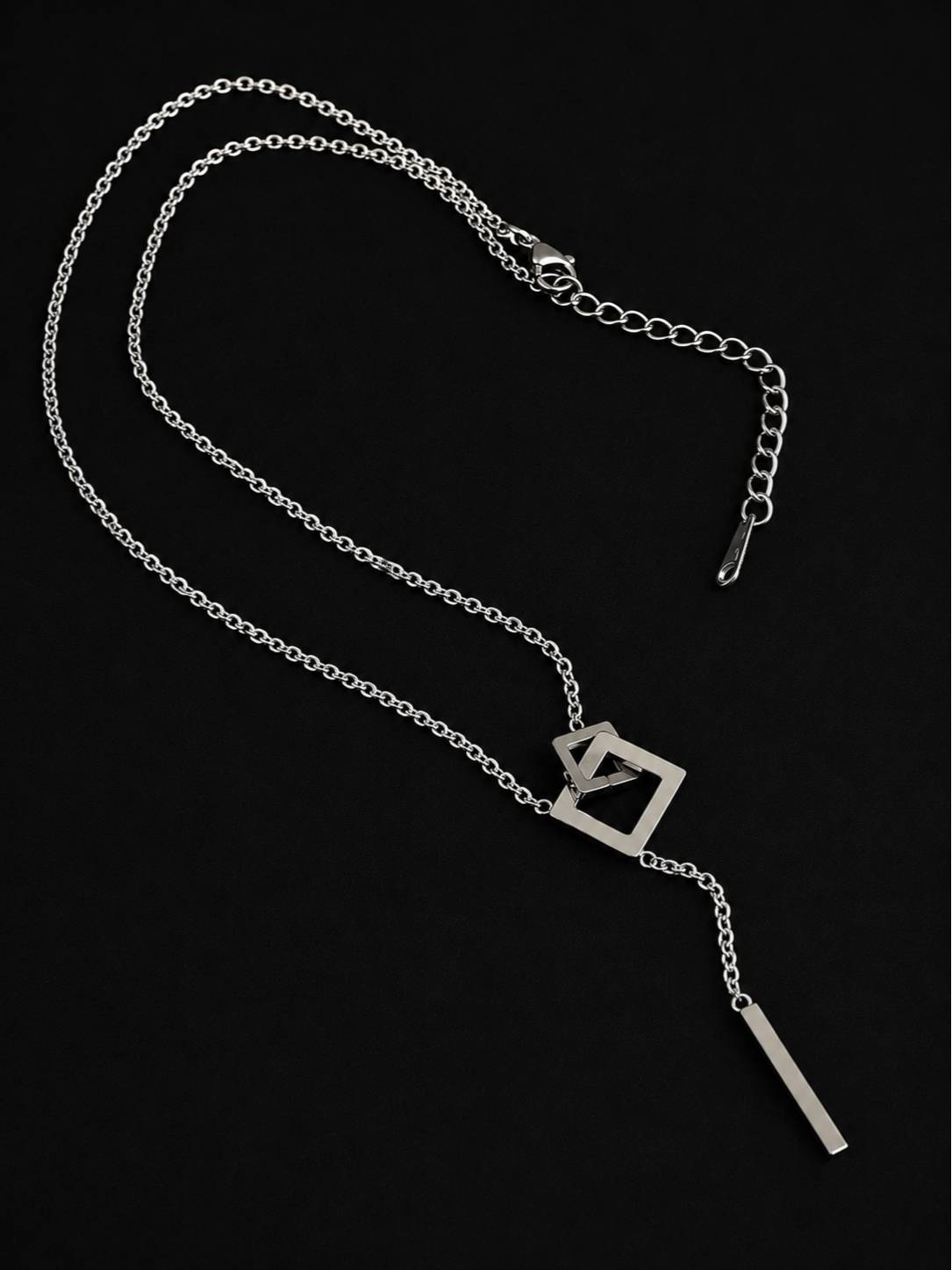 Full silver lariat necklace laid flat showing lobster clasp, extender chain, interlocked square pendant and bar drop