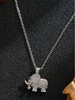Silver-tone CZ elephant pendant necklace displayed flat on black textured surface