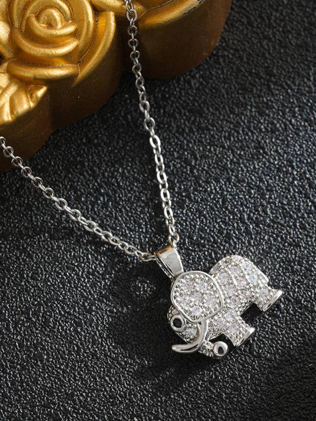 Close-up of pavé cubic zirconia elephant pendant with golden rose prop in background