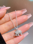 Hand holding silver elephant pendant necklace with pink long acrylic nails