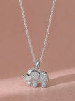 Silver CZ elephant necklace pendant lying flat on pink satin background