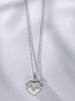 Front view of silver heart EKG pendant necklace on white fabric background