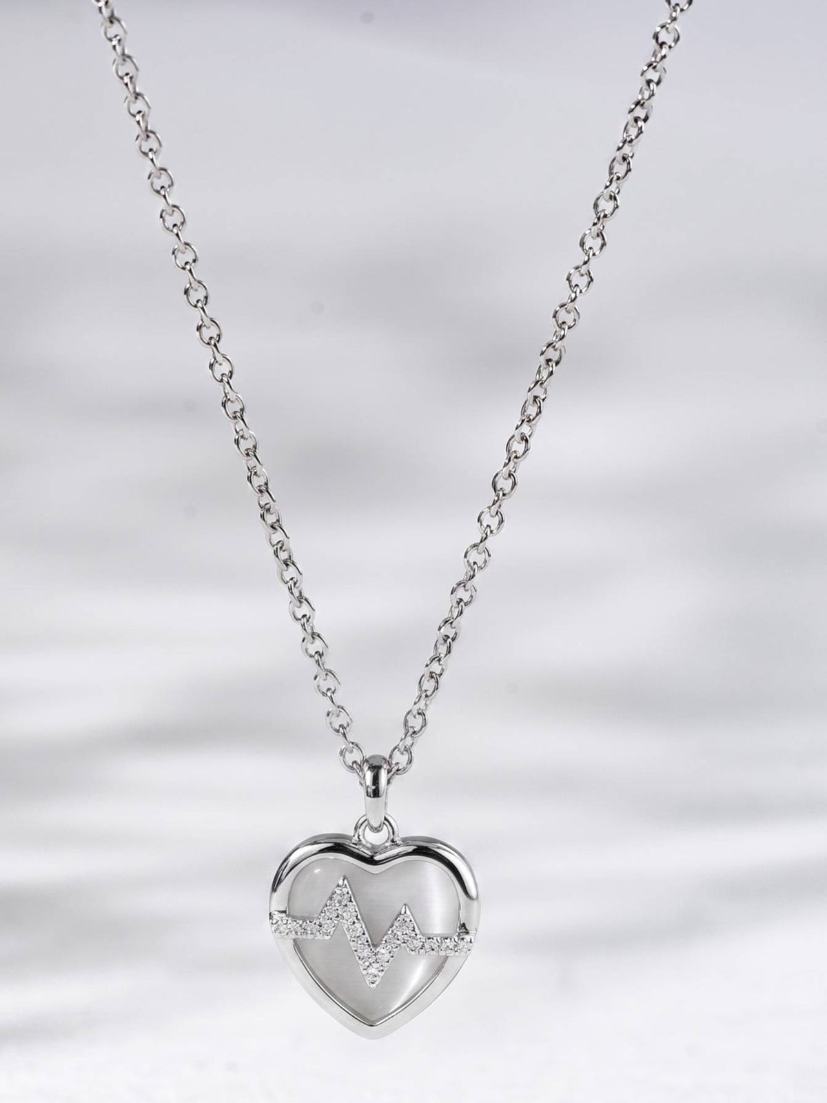 Full length silver cable chain with heart heartbeat pendant hanging centred on white background