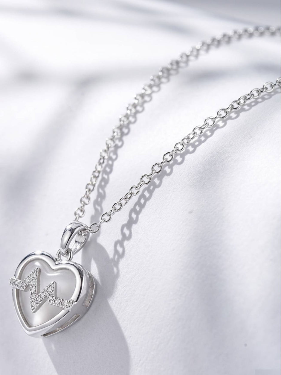 Close-up side angle of heart pendant showing cubic zirconia heartbeat motif and opalite inlay
