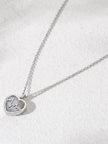 Angled flat-lay of silver heartbeat heart pendant necklace on textured white surface