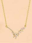 Front view of gold-plated CZ V-bar necklace showing marquise cluster and pavé curved bar against peach background