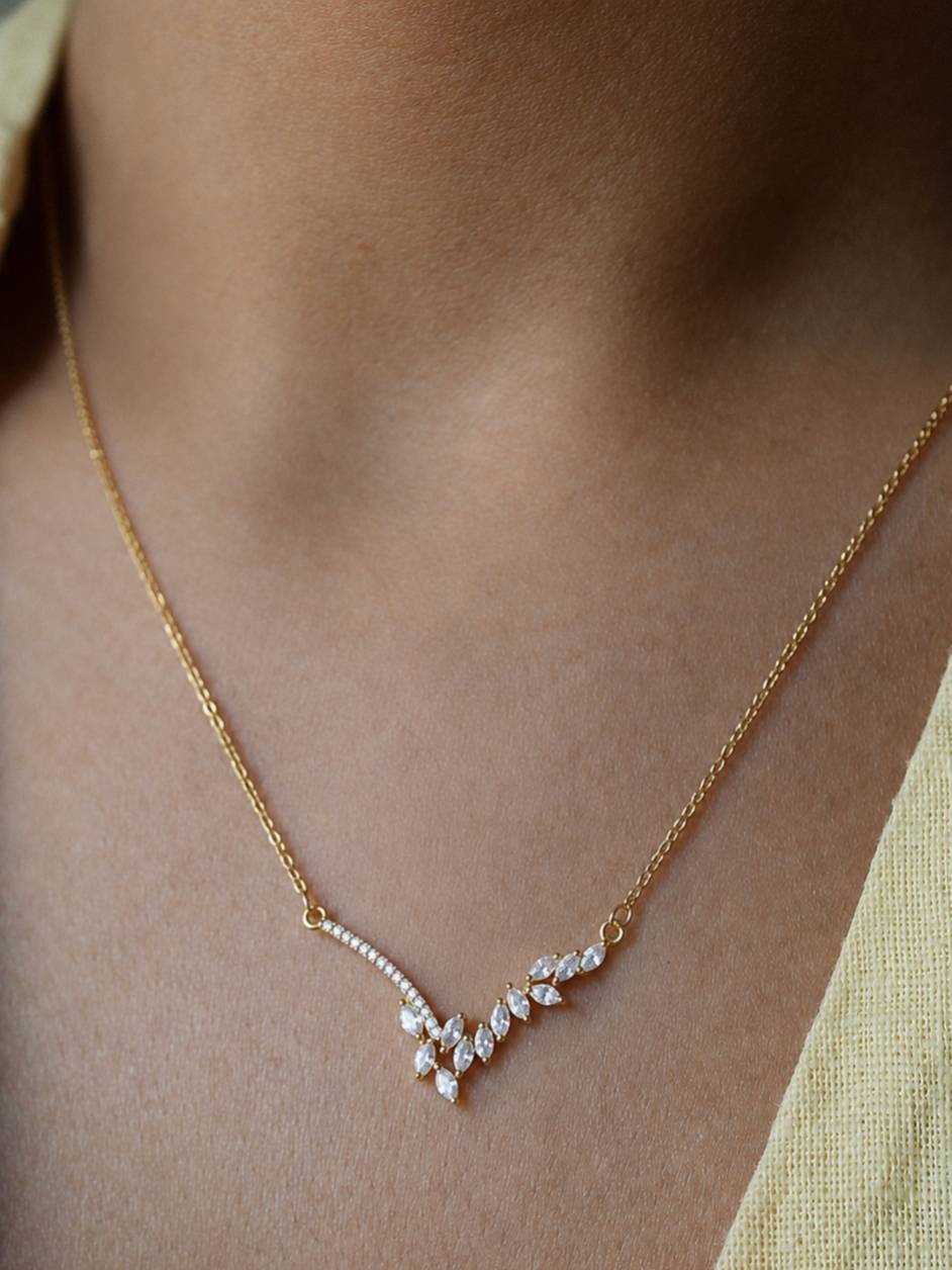 Model wearing gold-plated CZ marquise necklace at collarbone level styled with a yellow outfit