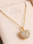 Gold-plated pave crystal heart pendant necklace laid flat on a cream jewellery box