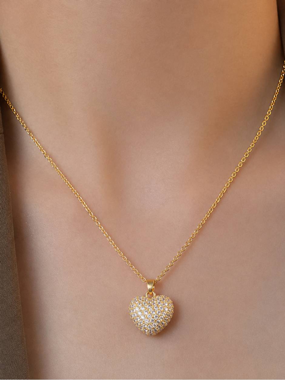 Gold pave heart pendant necklace worn around a woman's neck on bare skin