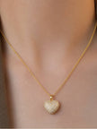 Gold pave heart pendant necklace worn around a woman's neck on bare skin