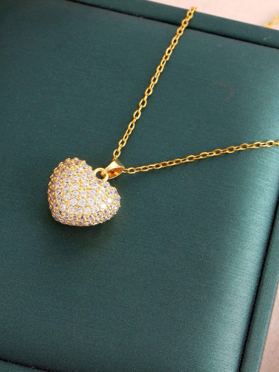 Close-up of gold-tone micro-pave heart pendant on a green jewellery display tray