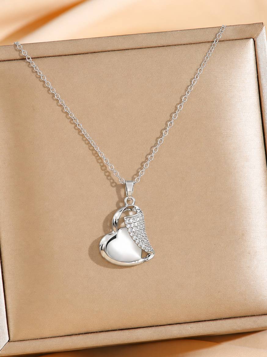 Silver heart pendant necklace with cubic zirconia wing detail displayed on a gold jewellery box