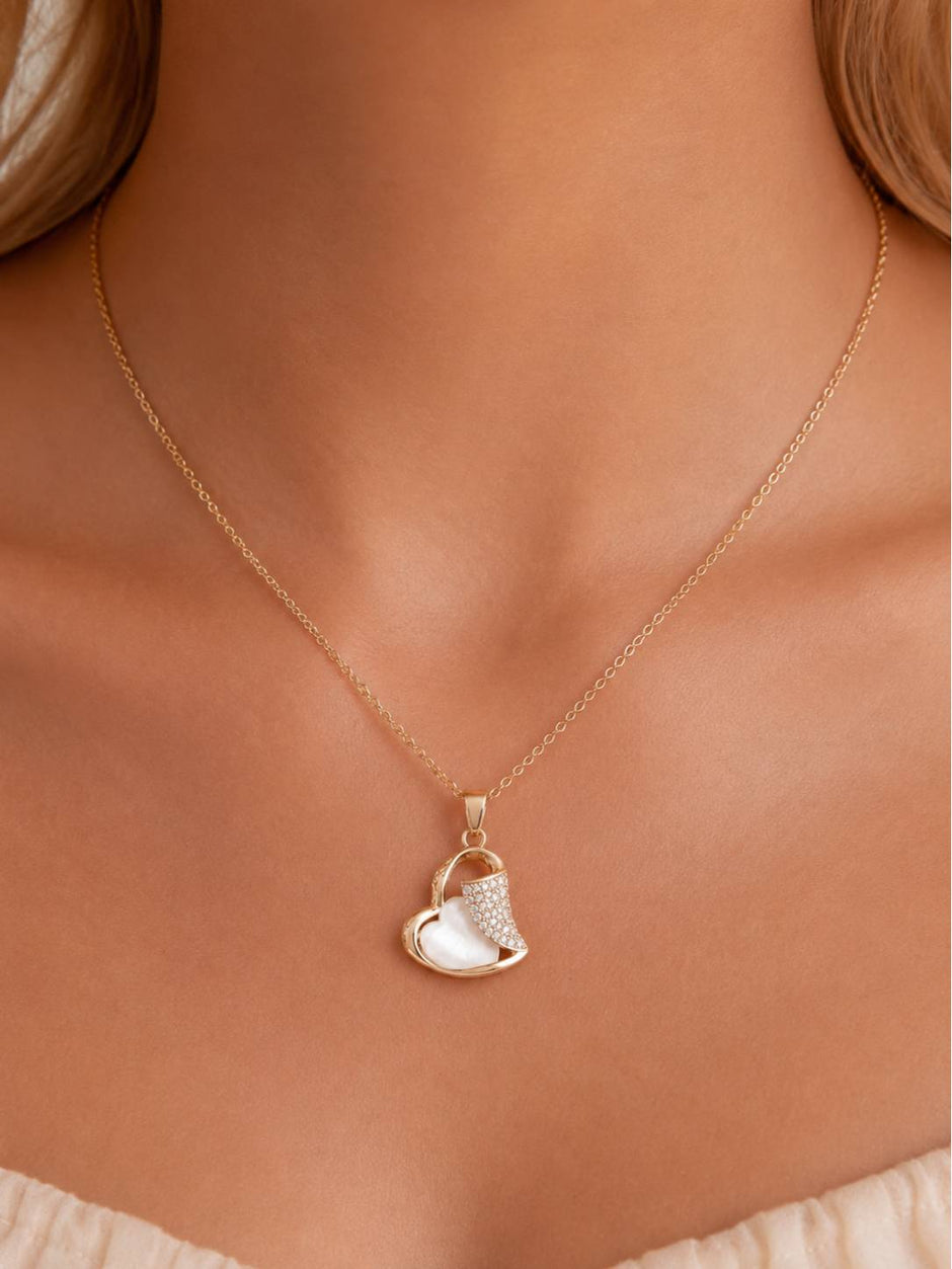Rose gold heart pendant necklace worn on a model's neckline over a white top