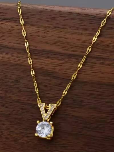 Gold-plated V letter crystal pendant necklace displayed flat on a dark wooden surface