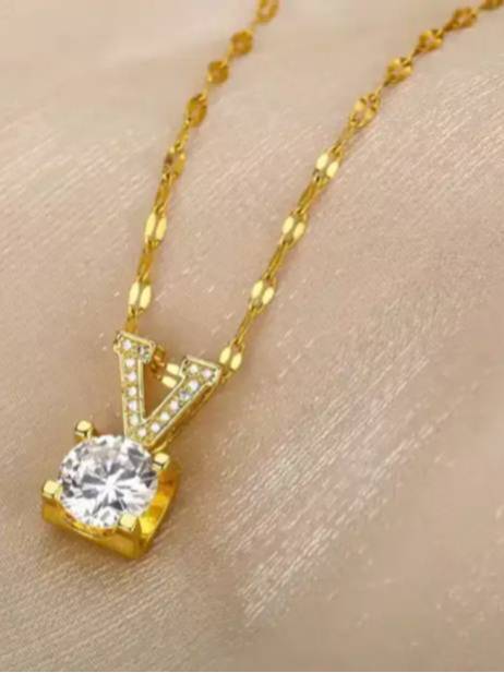 Close-up of V letter gold pendant with cubic zirconia stone resting on a model's wrist