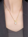 Model holding V initial pendant necklace in palm showing chain detail and zirconia stone up close