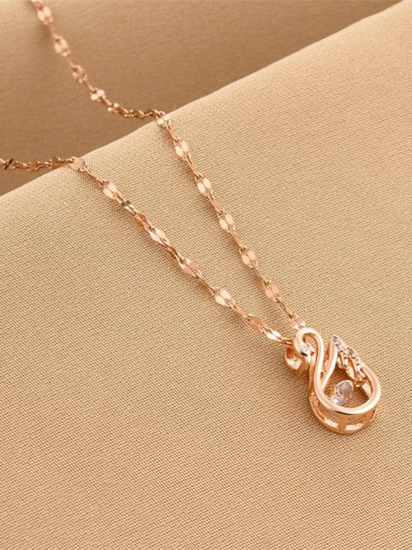 Close-up of rose gold swan pendant with zirconia stones on a textured beige surface