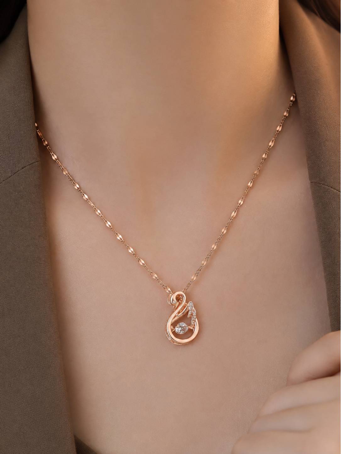 Rose gold swan necklace worn around a woman's neck over an olive green outfit