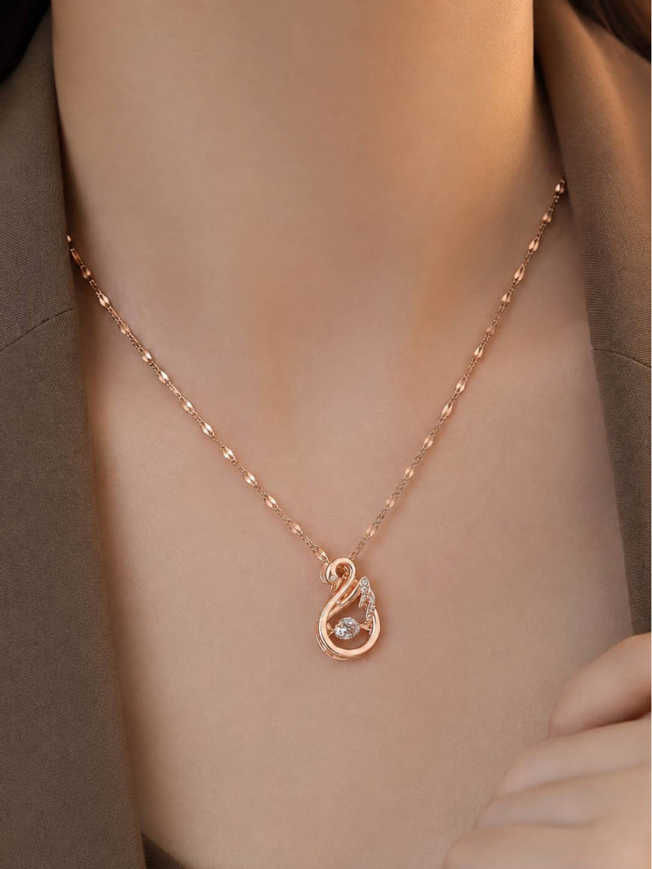 Rose gold swan necklace worn around a woman's neck over an olive green outfit