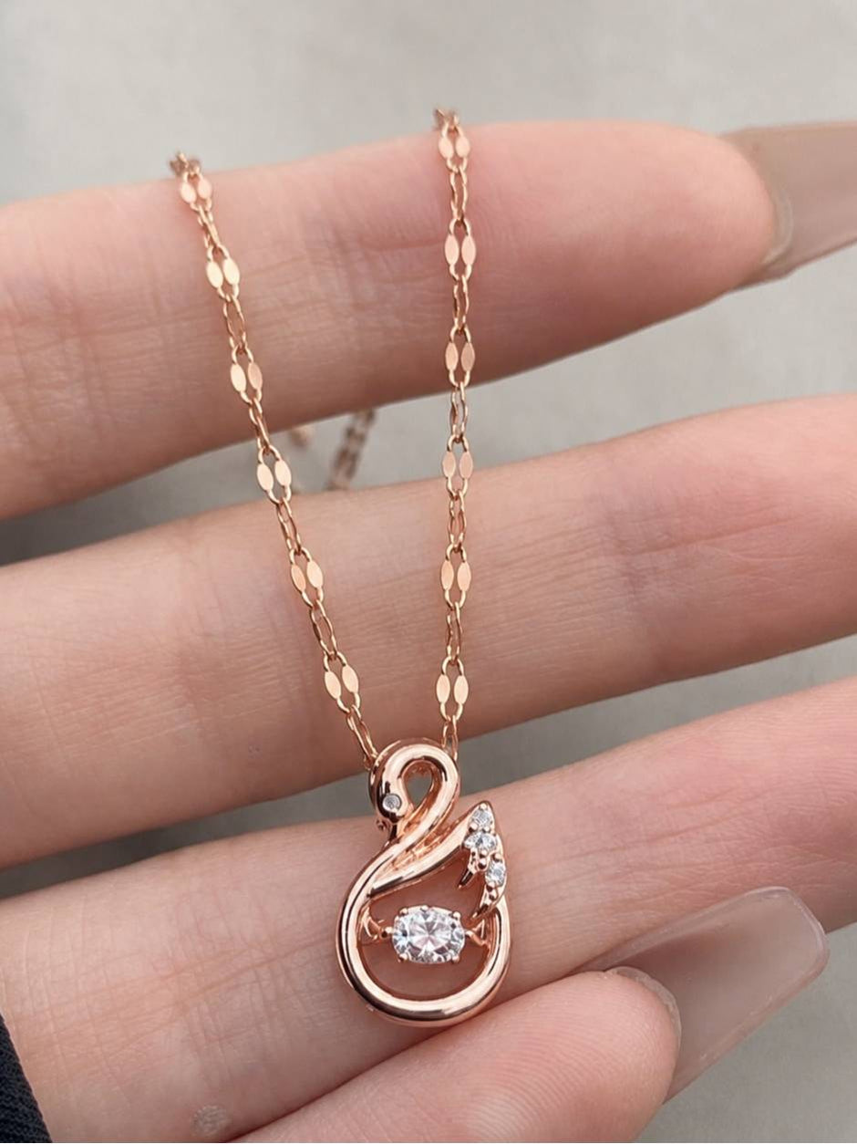 Rose gold swan pendant necklace held in a woman's open palm showing full chain detail