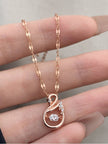 Rose gold swan pendant necklace held in a woman's open palm showing full chain detail