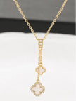 Double clover necklace laid flat on white surface showing full chain length and two-charm drop pendant detail