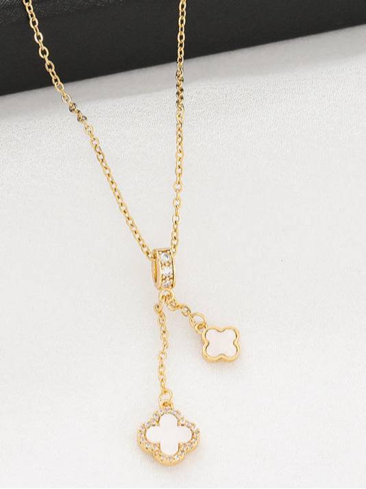 Close-up of double clover necklace on white surface showing CZ halo detail on the larger shell-inlay charm
