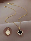 Two gold-plated clover pendant necklaces side by side, one with white shell inlay and one with black enamel inlay, both with crystal borders