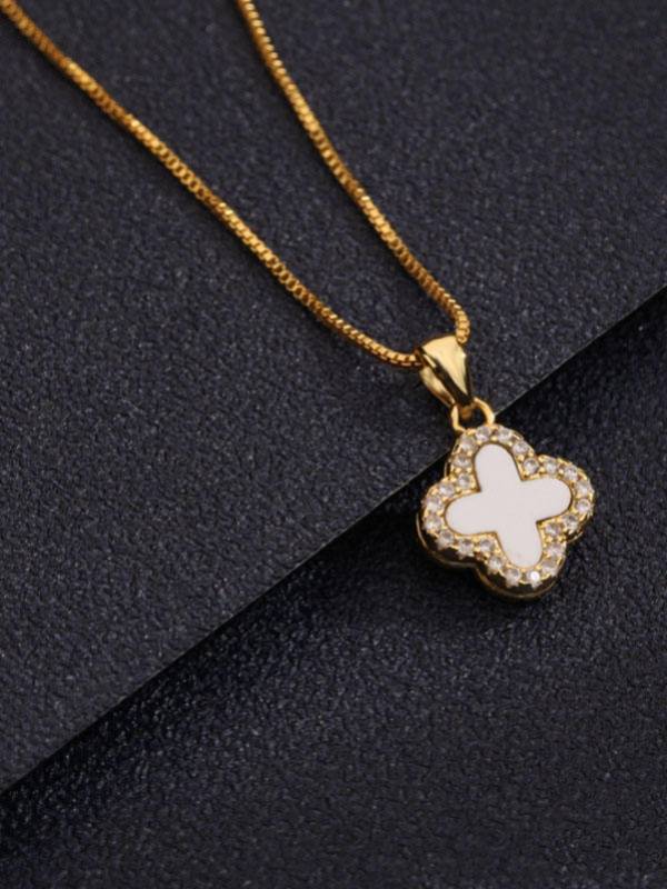 Close-up of gold-plated clover pendant with white shell inlay and crystal border on a slim box chain against dark background