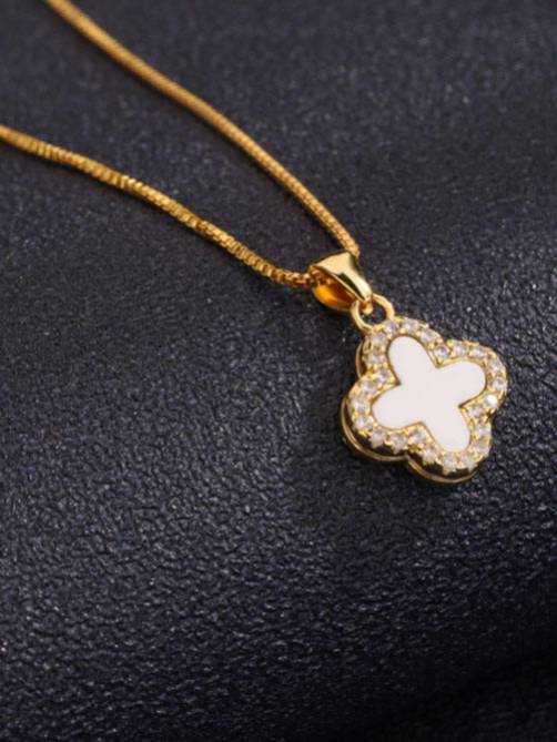 Gold-plated clover necklace with white shell inlay pendant lying flat on a dark surface showing full chain length