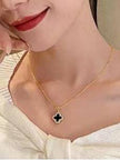 Woman wearing gold-plated black enamel clover pendant necklace over a white off-shoulder top