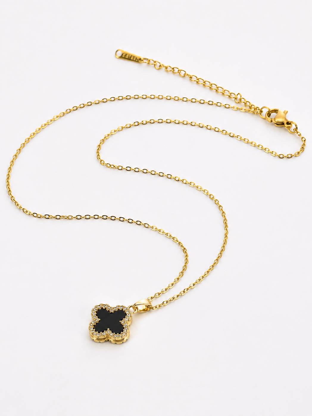Gold-plated black clover CZ pendant necklace laid flat on white background showing full chain length and lobster clasp