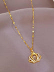 Gold-plated crown pendant necklace laid flat on a pink satin fabric surface
