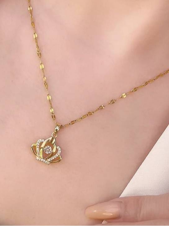 Gold-plated crown pendant necklace worn on a woman's collarbone showing chain drape