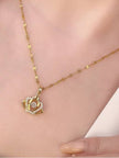 Gold-plated crown pendant necklace worn on a woman's collarbone showing chain drape