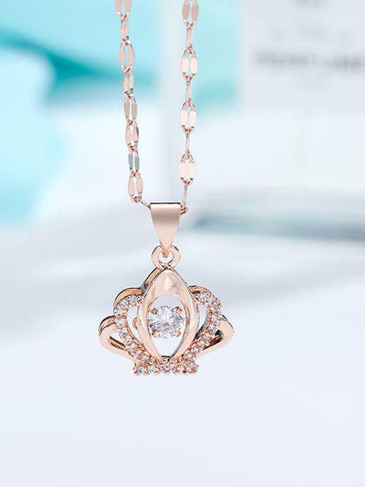 Close-up of rose gold crown pendant showing pavé zirconia detailing and oval-link chain against blue background