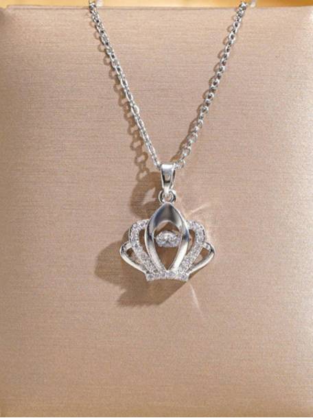 Silver crown pendant necklace with pavé crystals and floating centre stone laid on a beige display surface