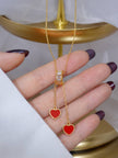 Close-up of gold dual heart lariat necklace held in a woman's palm showing crystal slider detail