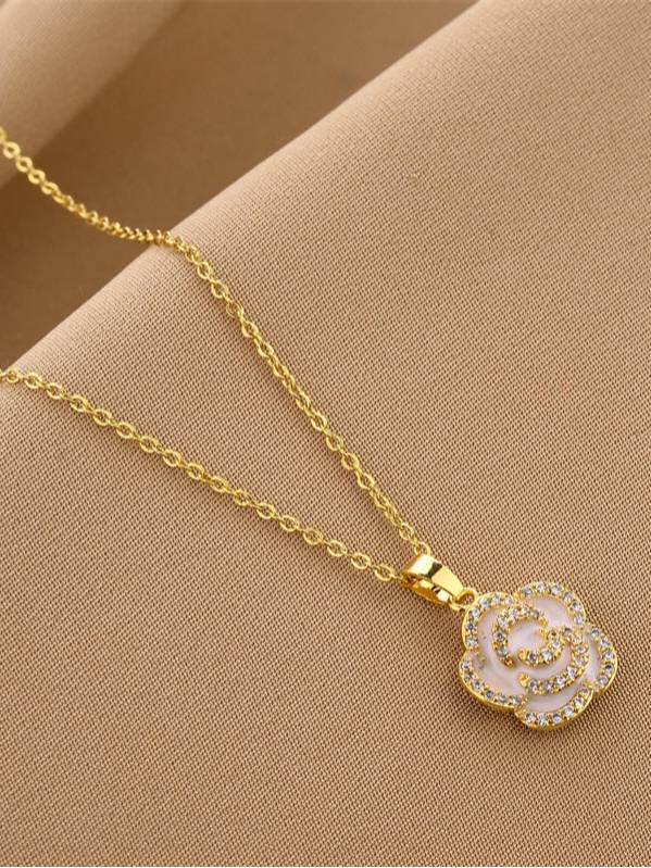 Close-up of gold-plated rose flower pendant with cubic zirconia stones on a beige fabric surface