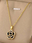 Gold-plated black enamel rose pendant necklace displayed flat on a beige jewellery tray