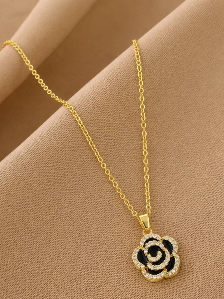 Close-up of rose pendant necklace with black enamel and cubic zirconia stones on draped beige fabric