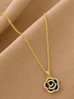 Close-up of rose pendant necklace with black enamel and cubic zirconia stones on draped beige fabric