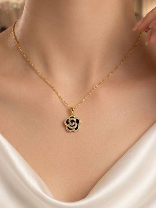 Model wearing gold-plated black enamel rose pendant necklace over a white satin outfit